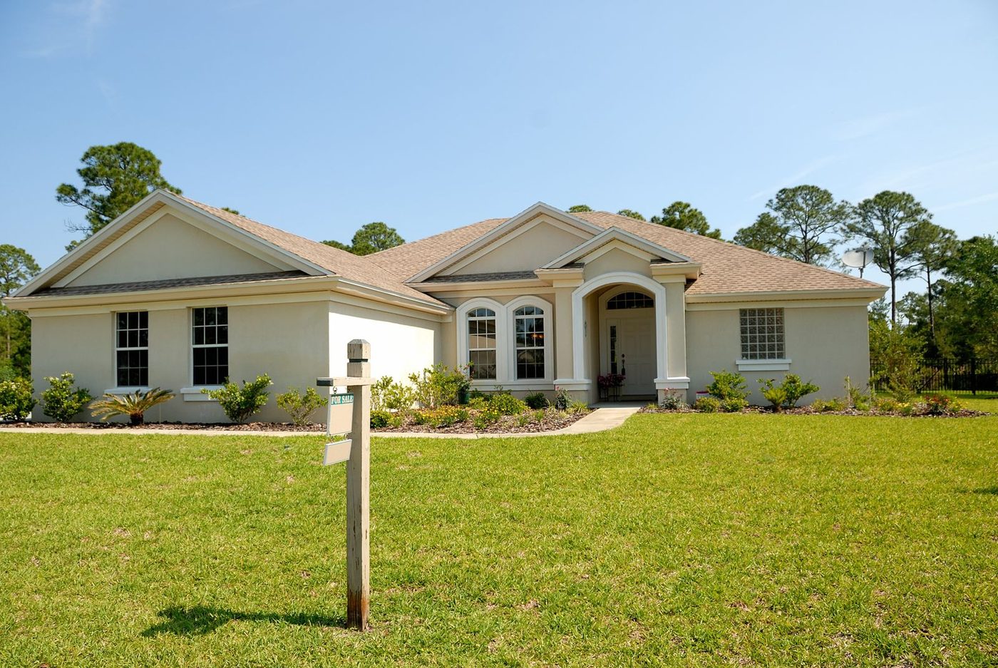 Single-story home with a light tan multi-gable asphalt-shingle roof under blue sky