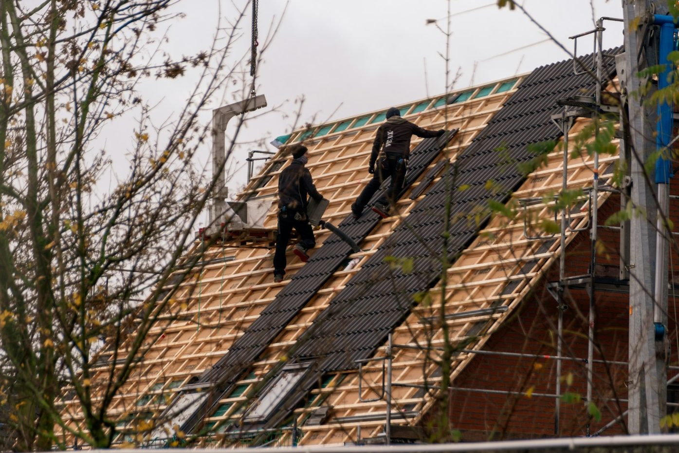 Crew installing dark shingles on a steep residential roof